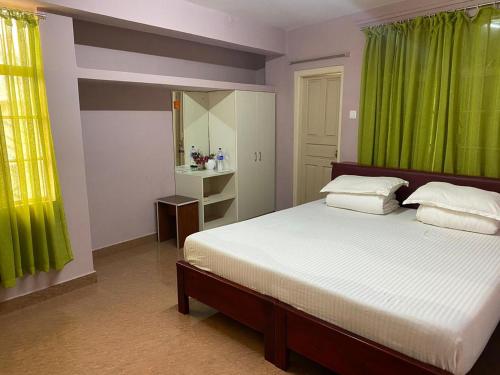 Schlafzimmer mit einem großen Bett und grünen Vorhängen in der Unterkunft The Palm Guest House in Kohīma