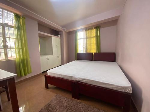 a bedroom with a bed and two windows at The Palm Guest House in Kohīma