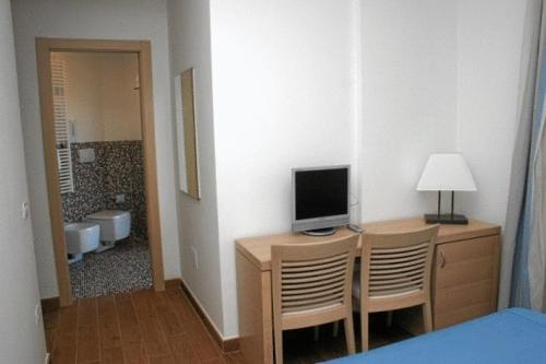 Habitación con escritorio, TV y cama. en Bi Hotel en Porto Ercole
