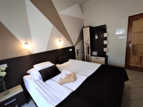 um quarto com uma cama grande com lençóis brancos e almofadas em Oázis Panzió em Makó