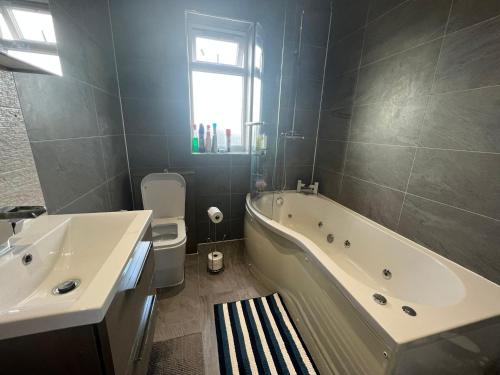 a bathroom with a tub and a toilet and a sink at Deluxe Homestay near Tottenham Hotspur Stadium in London