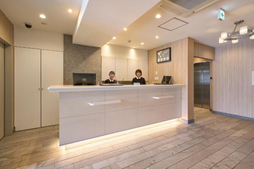 two women sitting at a reception desk in an office at Hotel Axia Inn Sapporo Susukino in Sapporo