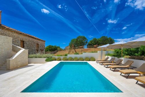 a pool with chairs and umbrellas next to a house at Villa Vitassi in Pula
