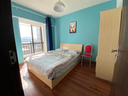 a bedroom with blue walls and a bed and a red chair at 合家欢 in Kunming