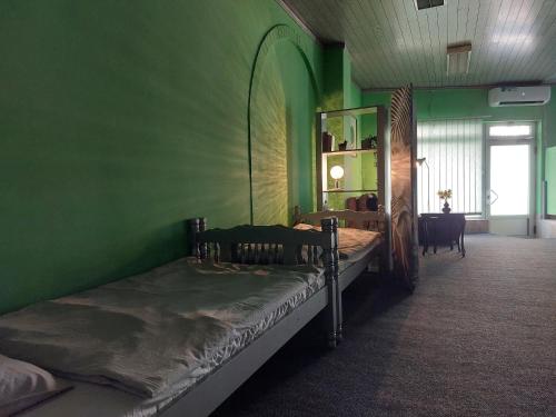 een groene kamer met 2 bedden en een spiegel bij Mila Studio in Bač