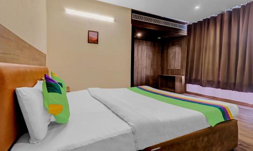 a bedroom with a bed with white sheets and colorful pillows at Treebo Edesia in Lucknow