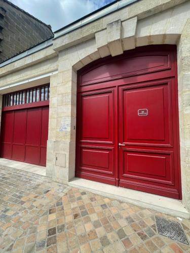 une paire de portes rouges de garage sur un bâtiment dans l'établissement LES CHAMBRES DE MARIE, à Bordeaux