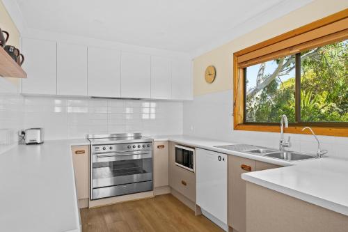 a white kitchen with a sink and a window at Port of Call - Port Willunga - C21 SouthCoast Holidays in Port Willunga