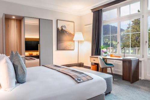 a hotel room with a bed and a desk at Villars Palace in Villars-sur-Ollon