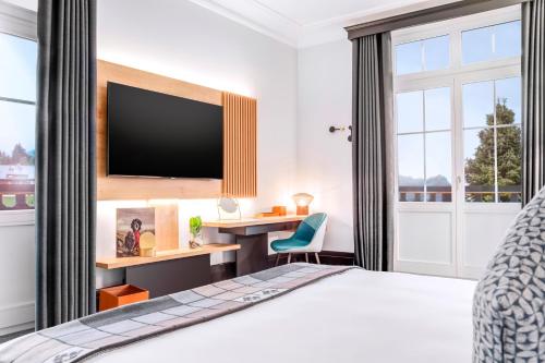 a bedroom with a bed and a desk with a tv at Villars Palace in Villars-sur-Ollon
