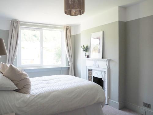 a bedroom with a bed with a fireplace and a window at Coorie Away - Kirkcudbright in Kirkcudbright