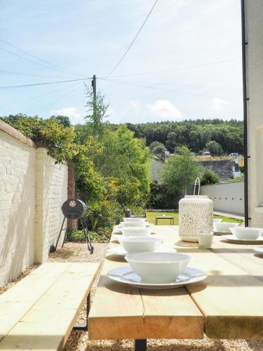 a long wooden table with bowls and plates on it at Coorie Away - Kirkcudbright in Kirkcudbright