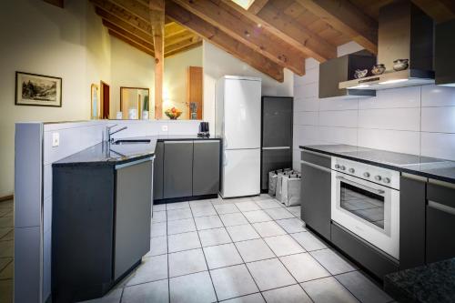 a large kitchen with white appliances and black counter tops at Apartments Patricia in Zermatt