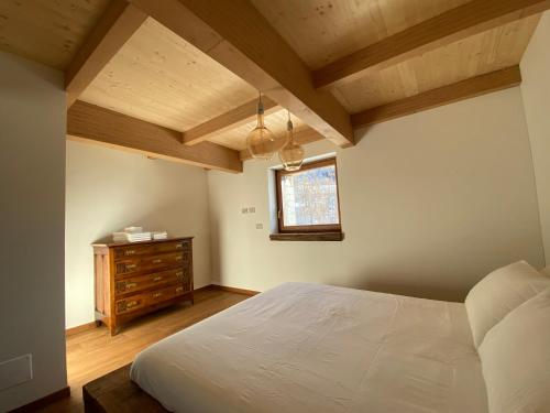 a bedroom with a bed and a dresser and a window at La Croche - Lo Marmotin in Chamois