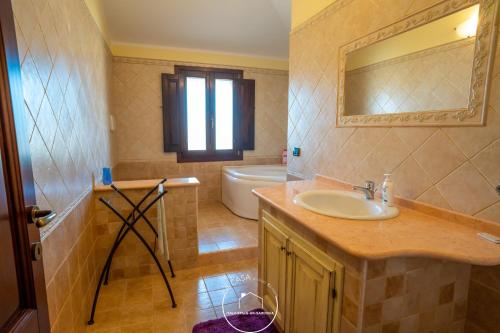 La salle de bains est pourvue d'un lavabo, d'une baignoire et d'un miroir. dans l'établissement La casa, à Terralba