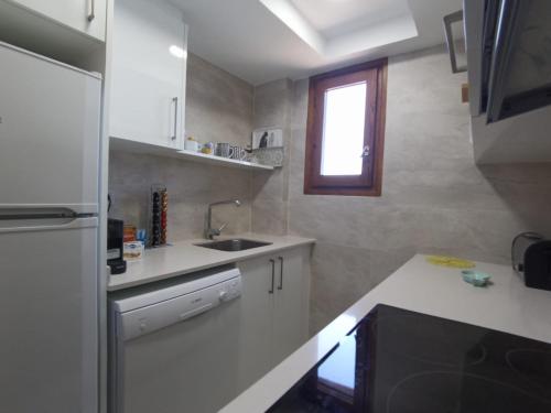 a white kitchen with a sink and a window at Albatros House in L'Escala