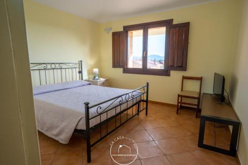 een slaapkamer met een bed, een bureau en een raam bij La casa in Terralba