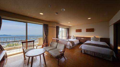 a hotel room with two beds and a balcony at KAMENOI HOTEL Atami in Atami