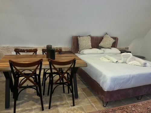 a room with two beds and a wooden table and chairs at Tish Hotel in Jerusalem
