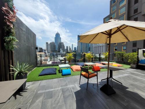 un patio con sombrilla, mesa y sillas en Citrus Suites Sukhumvit 6 by Compass Hospitality, en Bangkok