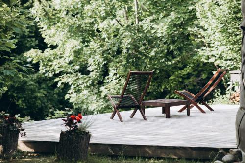 two wooden chairs and a bench on a patio at VasaRojaus Jurta in Birštonas