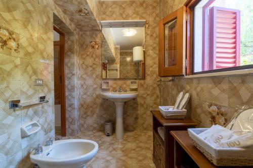 een badkamer met een wastafel, een toilet en een spiegel bij Villa Renè Locorotondo in Locorotondo