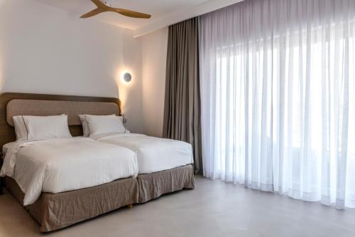 a bedroom with two beds and a large window at Muro Suites in Ornos