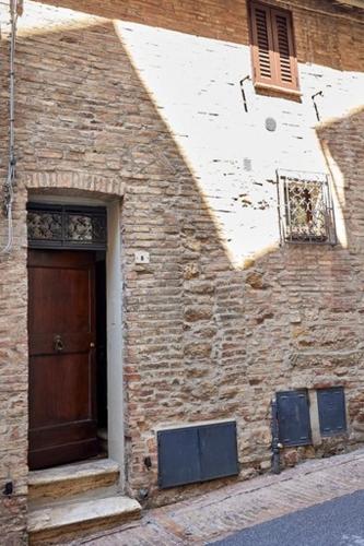 un edificio in mattoni con una porta marrone e una finestra di La casina di Iole a Montepulciano