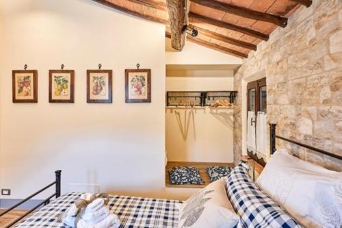 1 dormitorio con cama y pared de piedra en La casina di Iole en Montepulciano