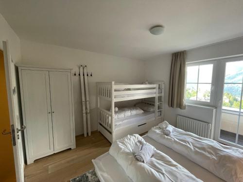 a white bedroom with two beds and a window at Alpenhof by AlpenTravel in Bad Gastein