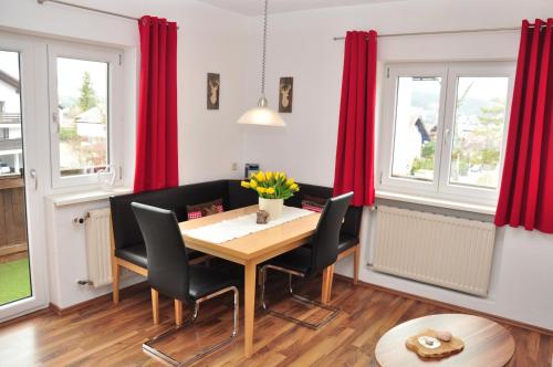 ゼーフェルト・イン・チロルにあるAppartment Haus Birgitの赤いカーテン、木製テーブルと椅子付きのダイニングルーム