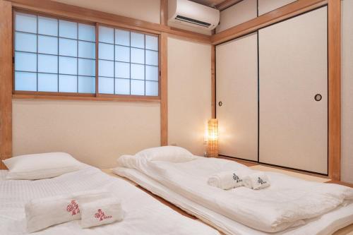 two beds in a room with a window at HANASTAY花渓居 · 柳（YANAGI) in Osaka