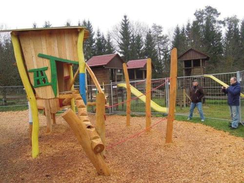 zwei Männer stehen neben einem Spielplatz mit Rutsche in der Unterkunft Ferienpark Lauterdörfle 4 in Hayingen