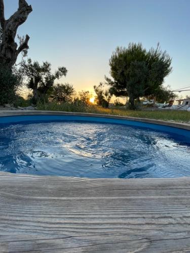 una piscina d'acqua con il tramonto sullo sfondo di Feudo Frammasi - Curte Glamping Experience a Salve