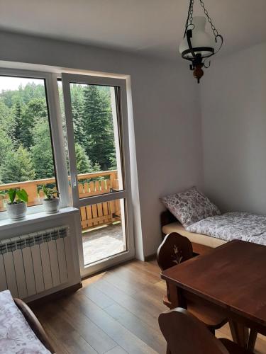 ein Wohnzimmer mit einem Esstisch und einem Fenster in der Unterkunft Dom Dobre Miejsce in Zawoja