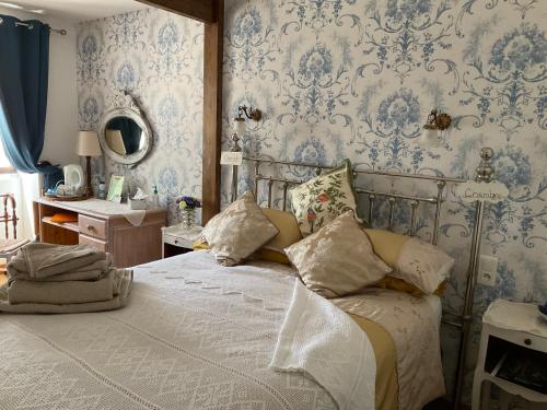 a bedroom with a bed with blue and white wallpaper at Le Jardin de Rose 24 FEUILLEBERT Romagne 86700 in Romagne
