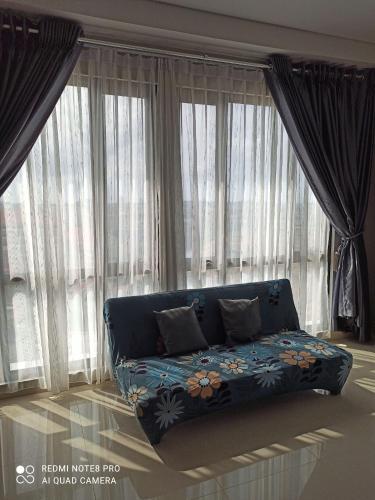 a blue couch in front of large windows at Palam Mansion at Apartment One Residence in Batam Center