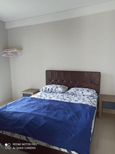 a bed with a blue comforter in a bedroom at Palam Mansion at Apartment One Residence in Batam Center
