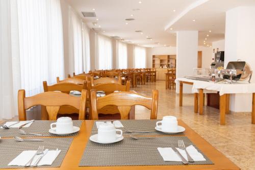 um restaurante com mesas e cadeiras de madeira e uma mesa em Hotel Montsia em Amposta