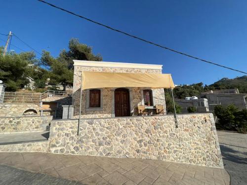 un petit bâtiment en pierre avec un auvent jaune dans l'établissement Panos Renos Studio, a cozy home by the beach!, à Kalymnos