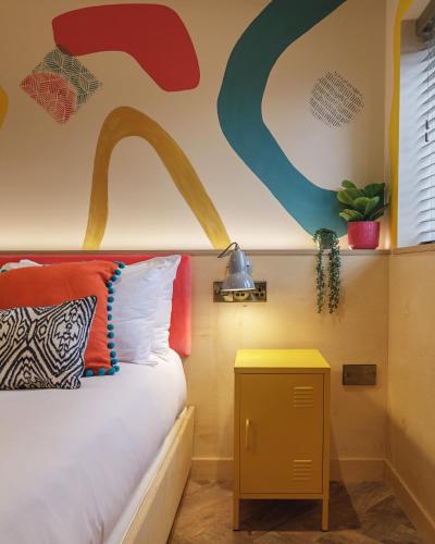a bedroom with a bed with a yellow nightstand next to a table at Ffolkes Arms Hotel in Hillington