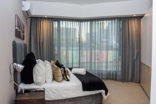 a bedroom with a bed with pillows and a window at The Menlyn Main Residents Trilogy in Pretoria