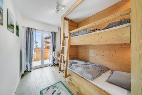 a bedroom with bunk beds and a balcony at In the heart of Crans, fireplace and parking in Crans-Montana
