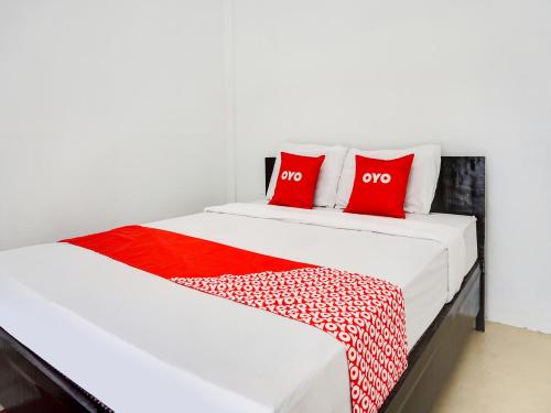 a bed with two red pillows on top of it at OYO 91544 Homestay Biru Blukid in Sidoarjo