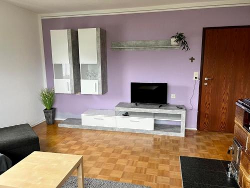 sala de estar con TV y paredes de color púrpura. en Ferienwohnung am Mattsee en Guggenberg