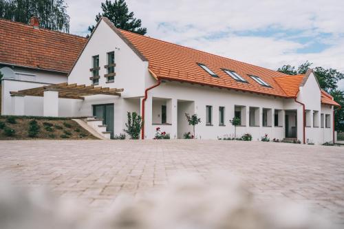 a white house with an orange roof at Kardamom Studio Apartman in Szigliget