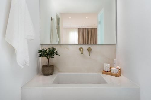 a white bathroom with a large white tub in a room at Cycladic Suites & Spa in Fira