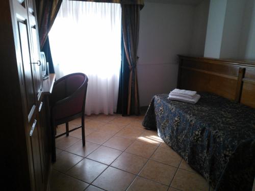 a bedroom with a bed and a chair and a window at Hotel Ristorante Antica Marina in Nicotera Marina