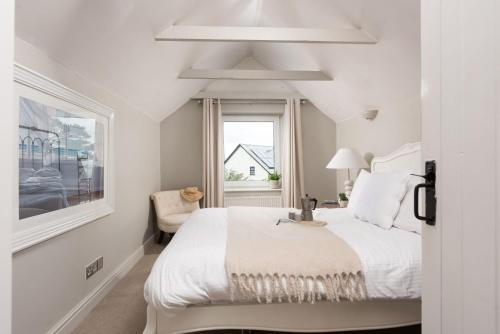um quarto branco com uma cama e uma janela em Spindrift, St Ives em St. Ives