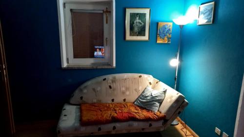 a couch in a room with a blue wall at Apt. BELLA VISTA nel Cuore della Valle di Cembra. in Segonzano